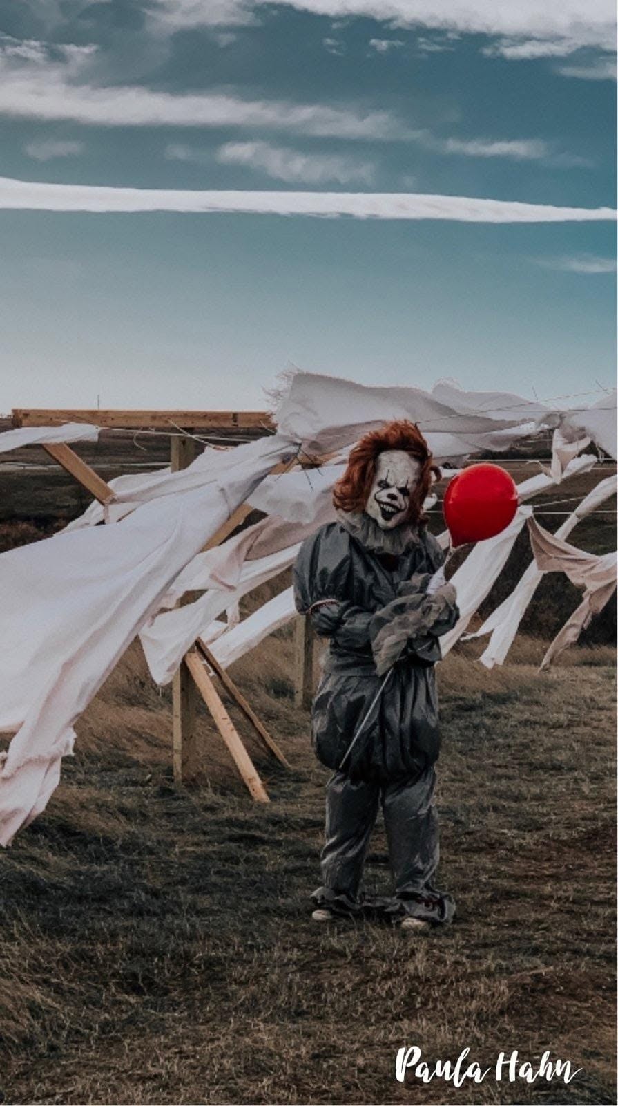 A costumed clown holding a red balloon at Dark Acres; photo credited to Paula Hahn